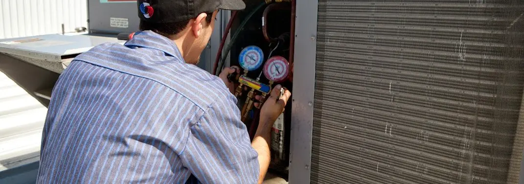 HVAC technician servicing a condenser unit in Hudson
